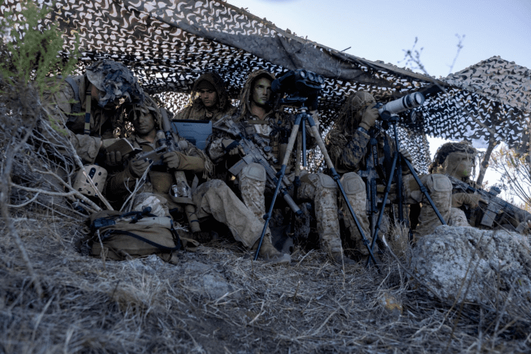 "Marine working at a secure computer station while enhancing cyber safety for soldiers, with digital threat symbols subtly in the background."