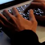 **Alt Text:** Close-up of a person monitoring suspicious network activity on a computer screen, symbolizing the Dover urgent cybersecurity threat.